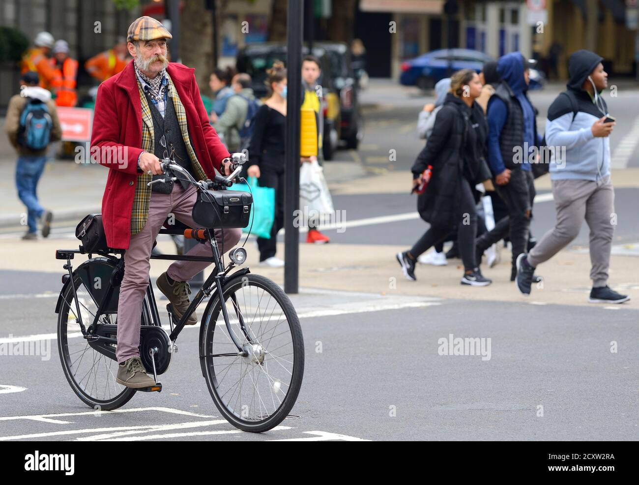 Londra, Inghilterra, Regno Unito. Un uomo vestito in bicicletta nello Strand Foto Stock