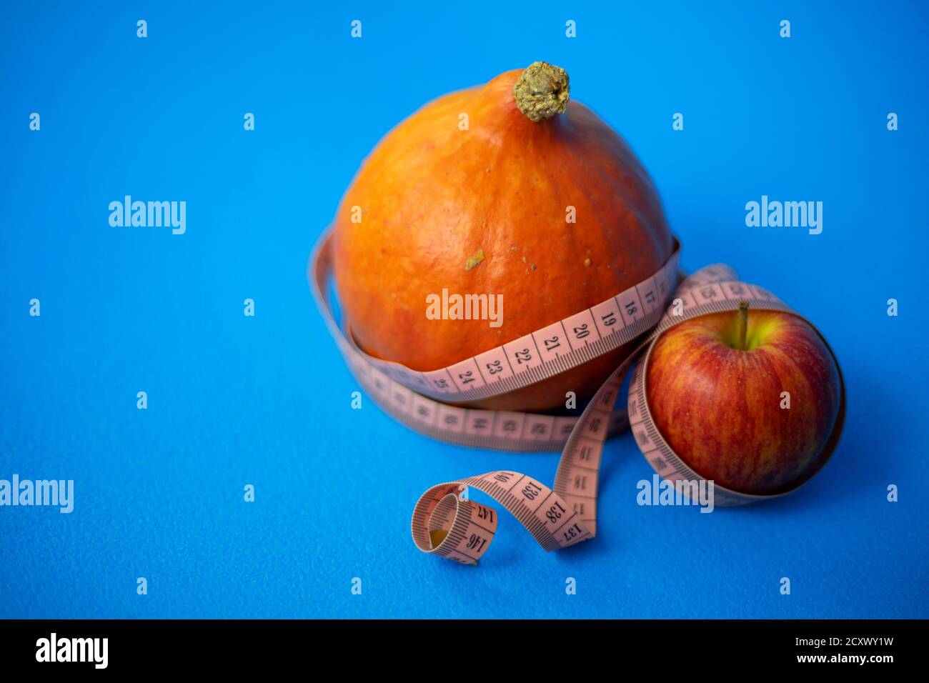 Dieta sana. Zucca e mela con nastro centimetrico su sfondo blu. Foto Stock