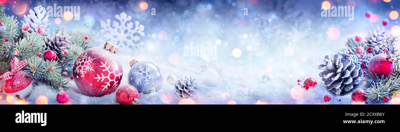 Banner decorazione Natale - innevato ornamento con pineconi su Abete Diramazioni e luci sfocate Foto Stock