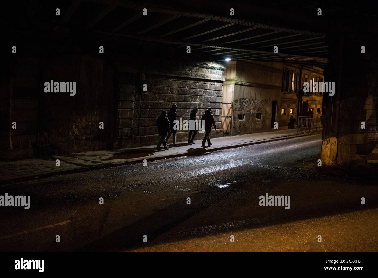 Sagome di diversi uomini che camminano sotto un ponte su una strada vuota a Edimburgo. Foto Stock