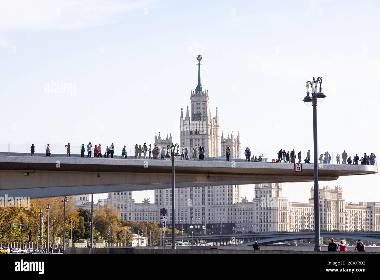 MOSCA, RUSSIA - 27 SETTEMBRE 2020: Il Ponte galleggiante con i turisti vicino al Parco paesaggistico di Zaryadye e all'alto edificio Kotelnicheskaya Embankment Foto Stock