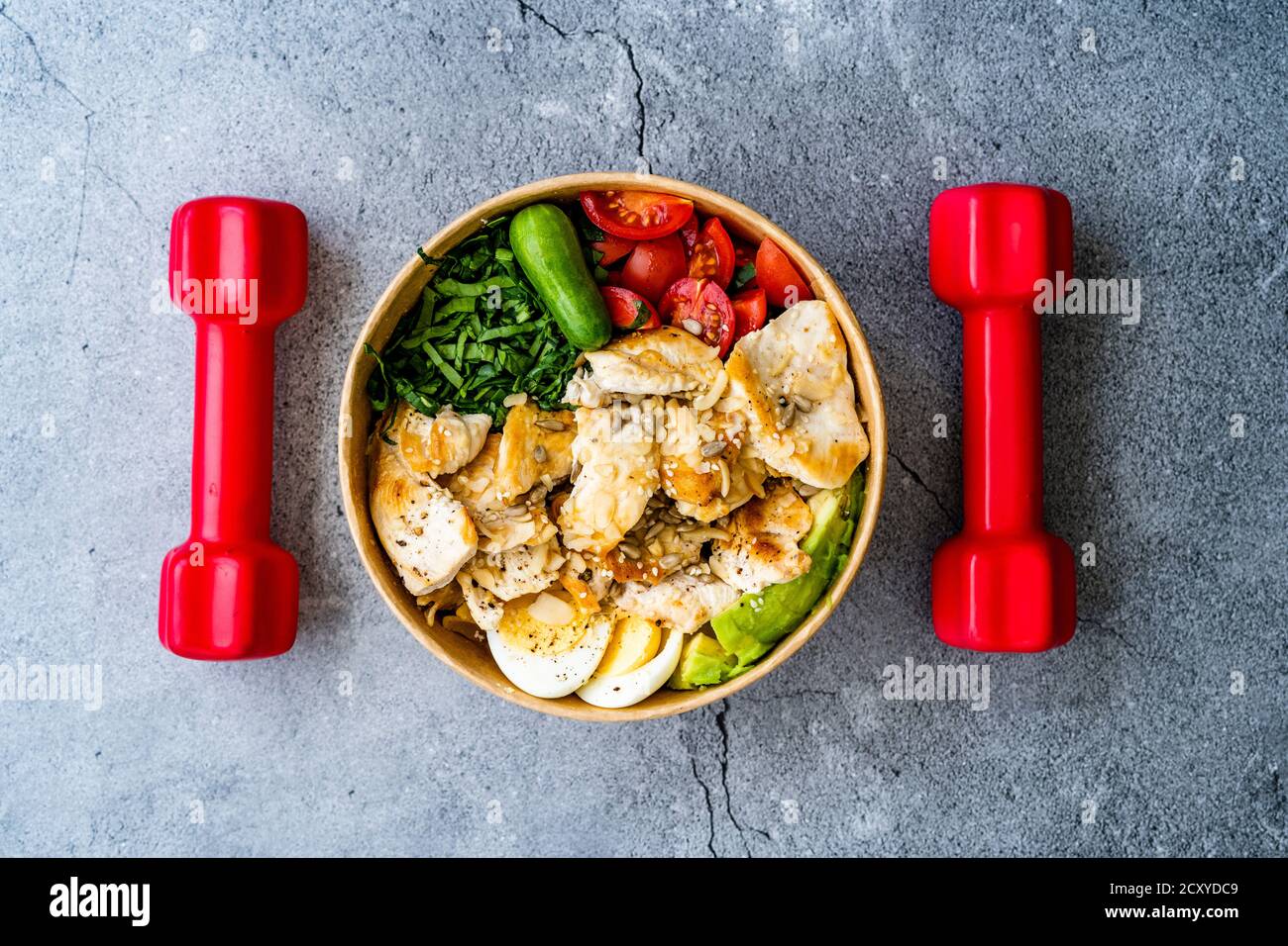 Sana Protein Fitness cibo Pollo, uovo, Spinach, avocado e cetriolo con attrezzature fitness Dumbbells per atleta in plastica Bowl. Pronto a mangiare. Foto Stock