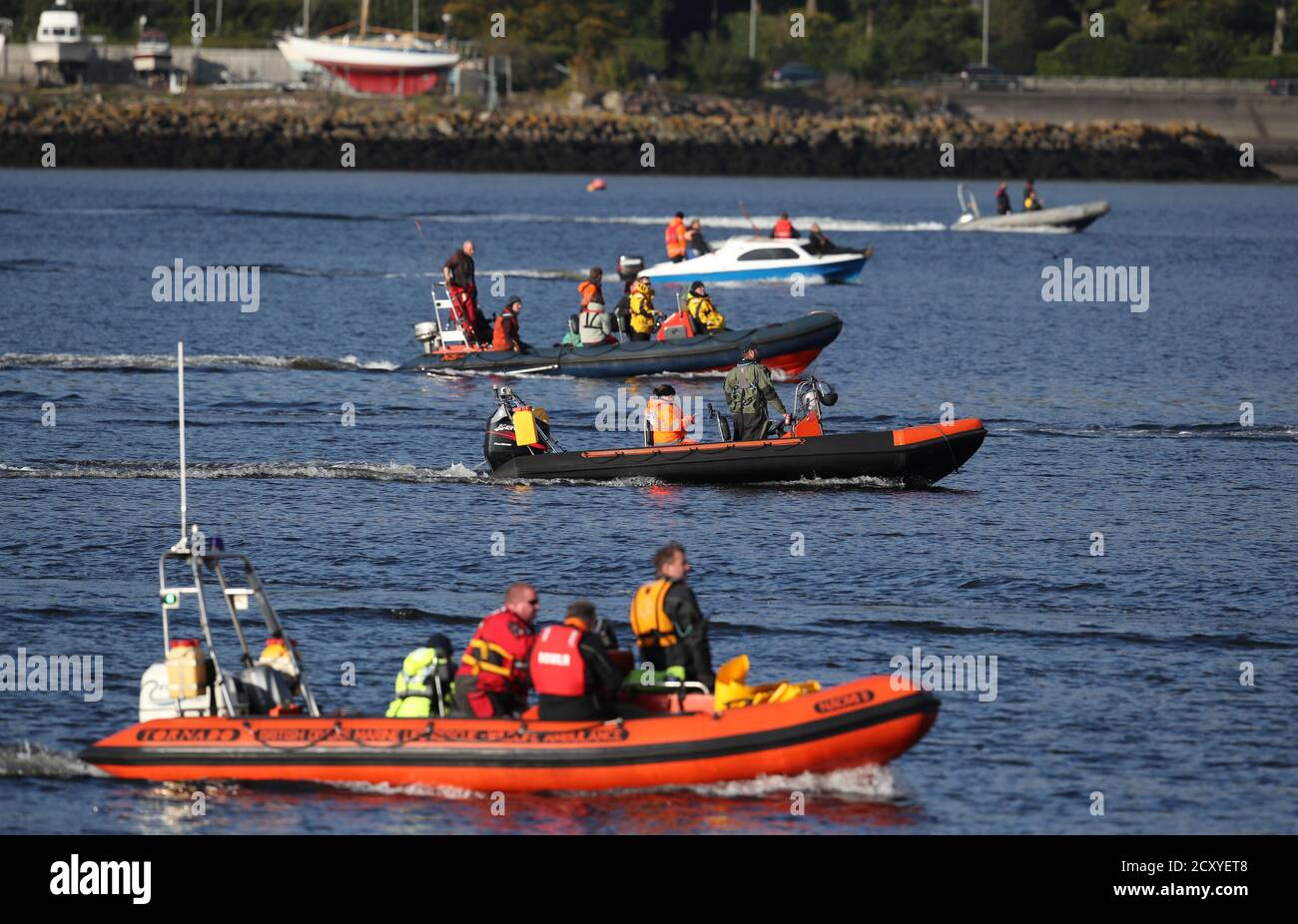 Una barca dal British Divers Marine Life Rescue viaggia insieme ad altre barche mentre tentano di spostare una balena a collo di bottiglia dalla Gare Loch. I soccorritori della British Divers Marine Life Rescue Medics (BDMLR) stanno utilizzando imbarcazioni nel tentativo di allevare un gruppo di balene settentrionali a collo di bottiglia fuori da Loch Long, in mezzo alla preoccupazione per il potenziale impatto derivante dall'esercizio Joint Warrior, un importante esercizio militare internazionale previsto per la zona, come le balene sono particolarmente sensibili ai suoni subacquei. Foto Stock