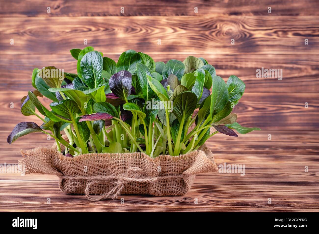 Foglie fresche di insalata in una ciotola di legno su legno rustico sfondo Foto Stock