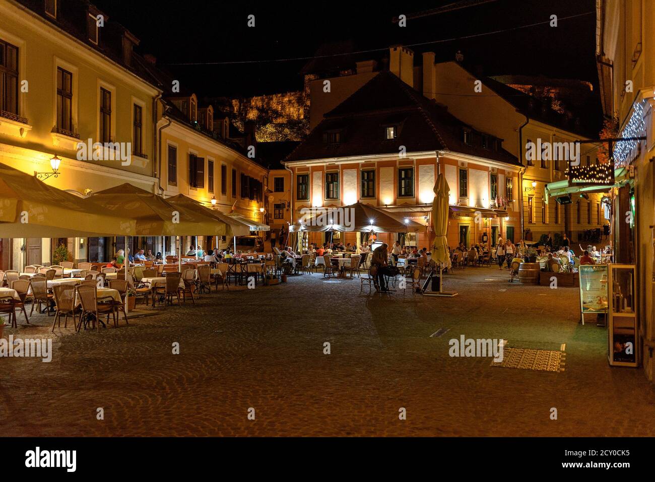 Persone che si siedono all'esterno su un ristorante e caffè all'aperto, godendosi la sera, su Kis Dobo ter di notte a Eger Foto Stock