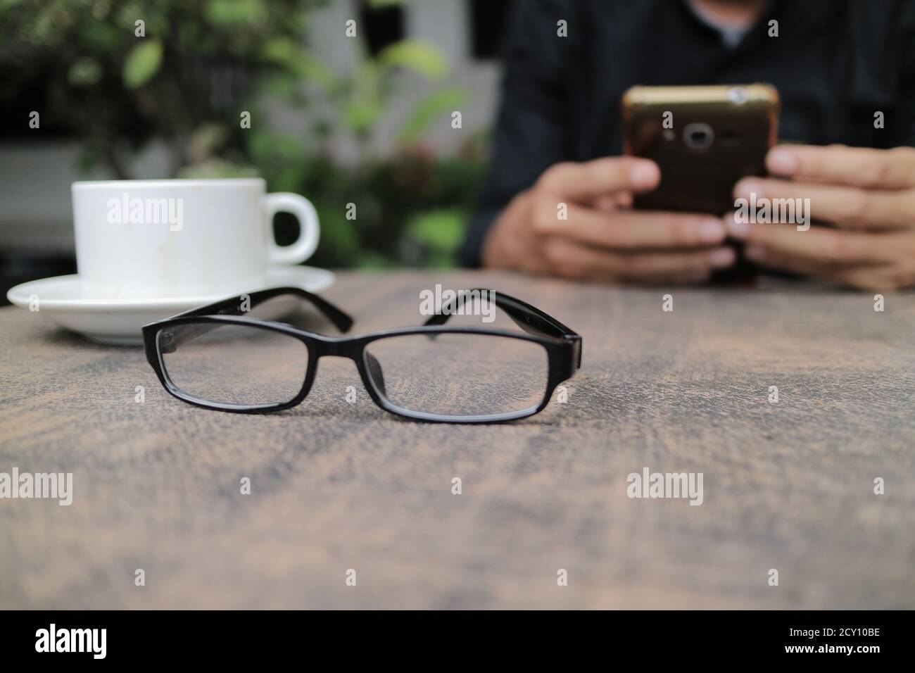 Bicchieri sul tavolo, una tazza di caffè e una mano di qualcuno Foto Stock