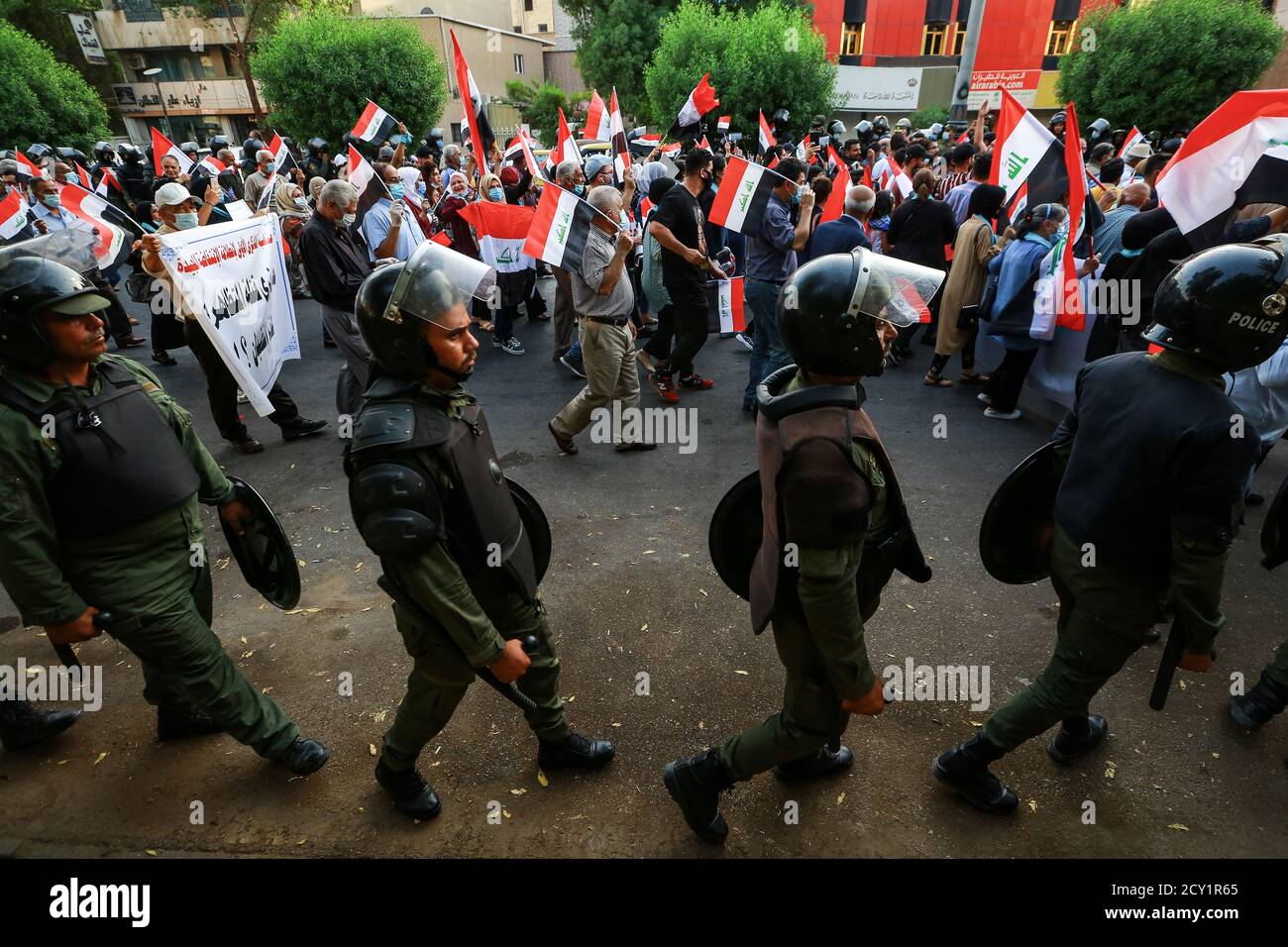 Baghdad, Iraq. 01 Ottobre 2020. Il personale della polizia accompagna i manifestanti che marciano da Piazza Firdos a Piazza Tahrir, durante un raduno per celebrare il primo anniversario delle manifestazioni anti-governative in Iraq di ottobre. Credit: Ameer al Mohammedaw/dpa/Alamy Live News Foto Stock