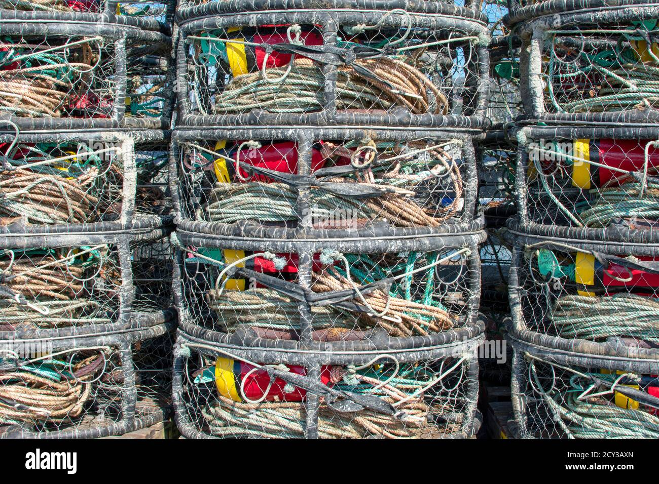 Gabbie commerciali per la pesca del granchio con boe rosse e gialle accatastate sulla base docking Foto Stock