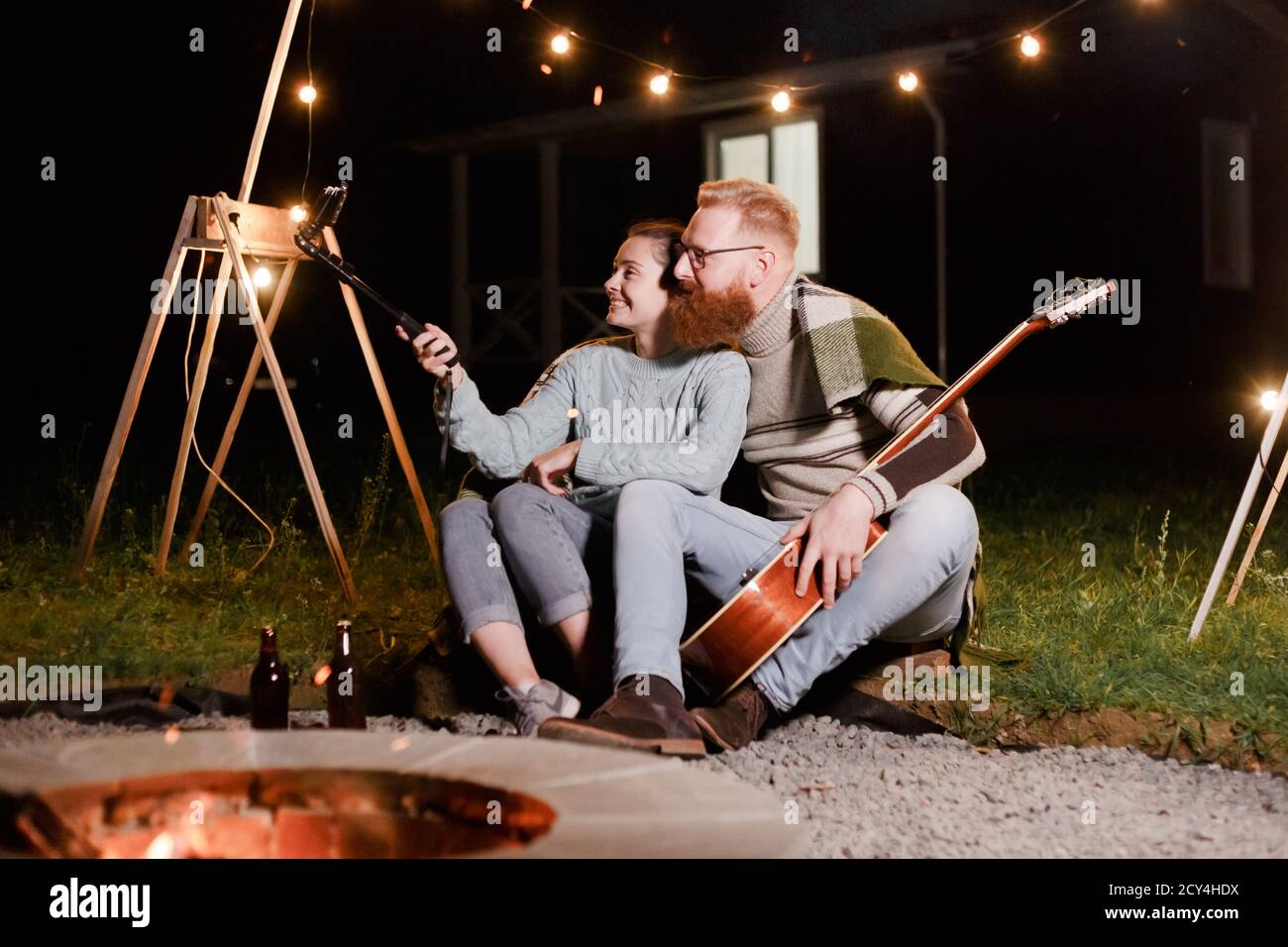 Felice coppia caucasica, donna bruna e uomo bearded con chitarra al picnic in campagna. Divertente coppia che fa selfie, sorridendo e divertirsi insieme Foto Stock