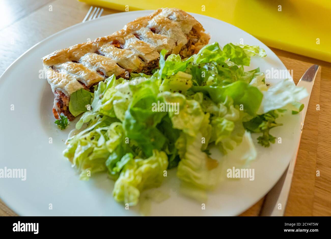 Cena a base di piatti bianchi che serve pasta sfoglia di barbabietola servita con insalata di lattuga verde Foto Stock