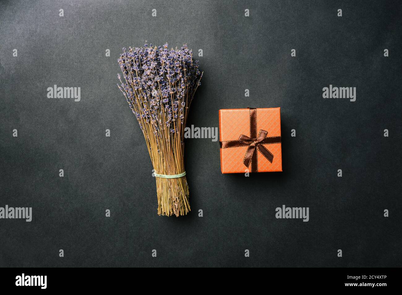 Bouquet di lavanda e confezione regalo con nastro su sfondo nero. Fiori secchi e una scatola a sorpresa. Vista dall'alto, layout piatto Foto Stock