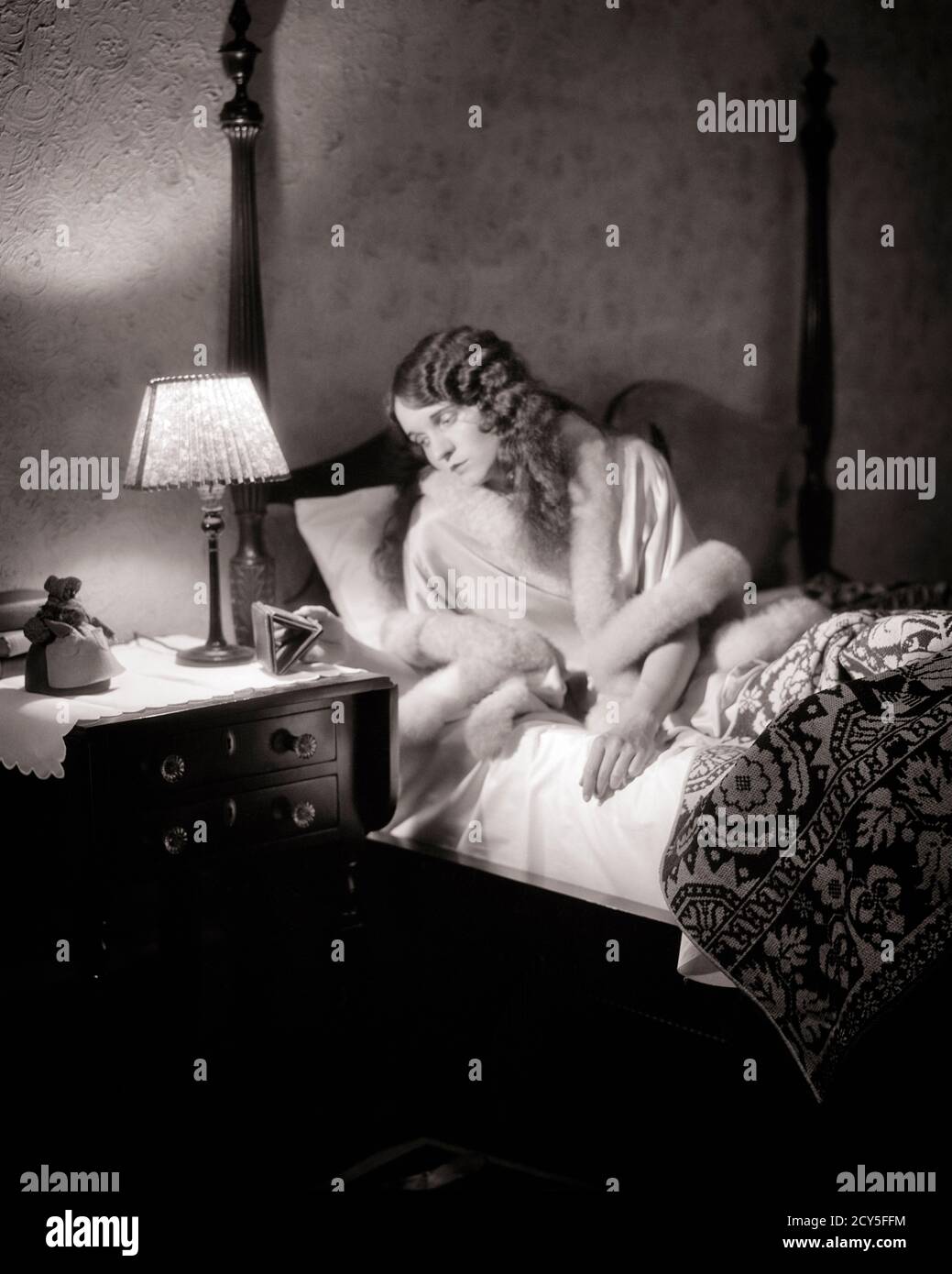 1920 ANNI 1930 DONNA INSONNE SVEGLIO SDRAIATA A LETTO GUARDANDO OROLOGIO SU COMODINO CON LAMPADA INSONNIA PREOCCUPAZIONE - N555 HAR001 HARS MOODY HEALTHINESS HOME VITA COPY SPACE MEZZA LUNGHEZZA SIGNORE PERSONE RISCHIO ESPRESSIONI DISTURBATO B&W INTERESSATO TRISTEZZA SOGNI BENESSERE INSONNE A IN ON AWAKE UMORE CONCETTUALE GLUM NOTTE STARE MISERABILE GIOVANE DONNA ADULTA NERO E BIANCO ETNIA CAUCASICA HAR001 VECCHIO ALLA MODA Foto Stock