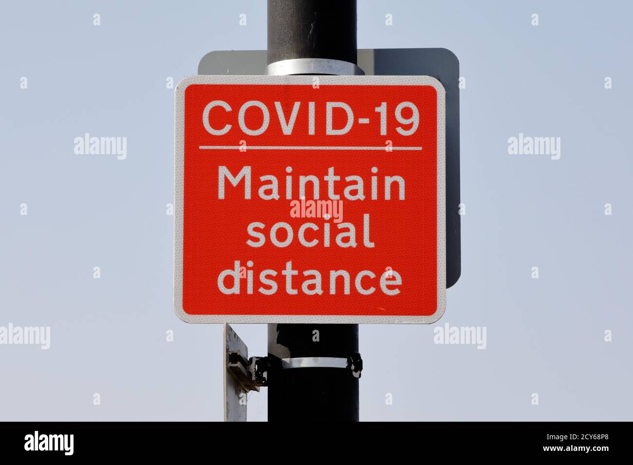 Un segno di metallo rosso quadrato che ricorda alle persone la distanza sociale Foto Stock