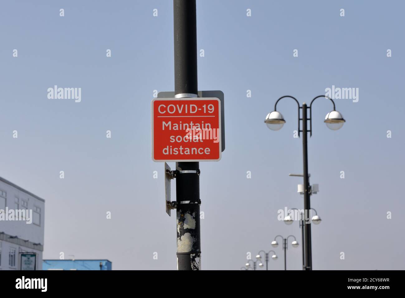 Un segno di metallo rosso quadrato che ricorda alle persone la distanza sociale Foto Stock