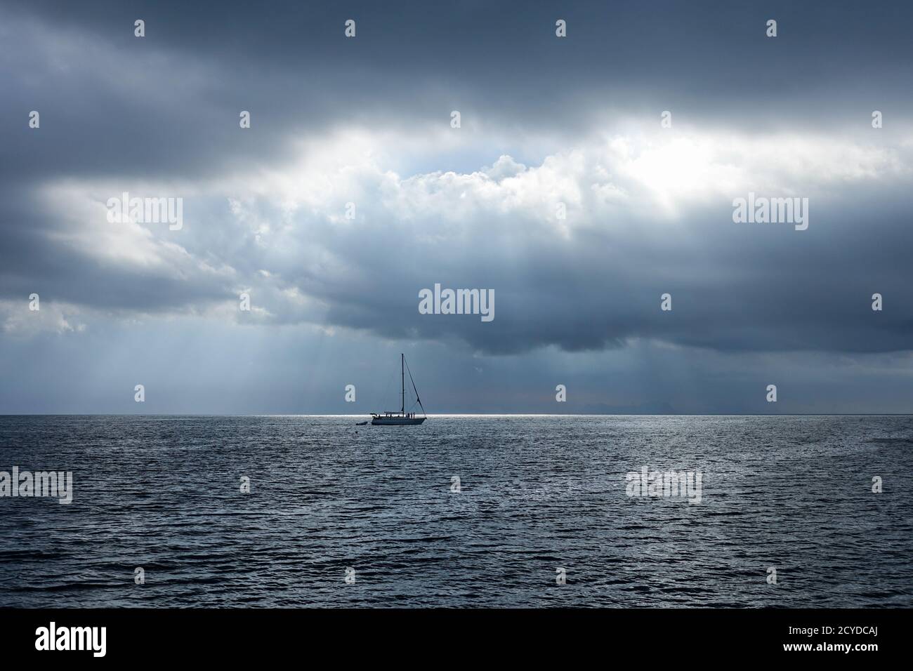 Barca a vela nel mare scuro, solo pochi raggi di luce illuminano il mare COLOMBIA Foto Stock