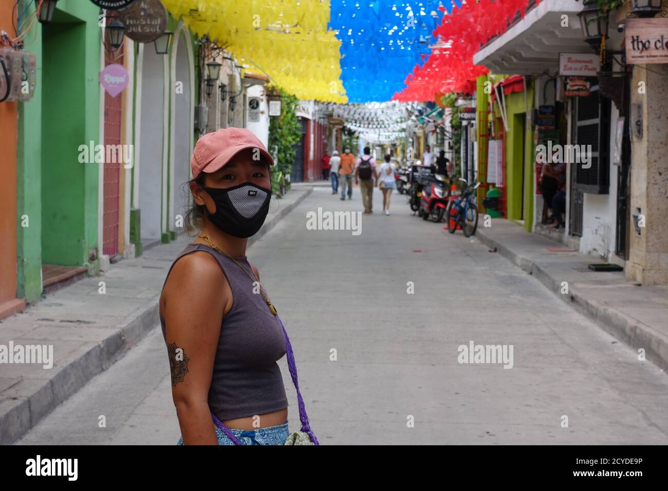 Donna con maschera e occhiali da sole a uso multiplo sotto bandiere durante la quarantena covid-19 a Cartagena, Colombia. 2020 Foto Stock
