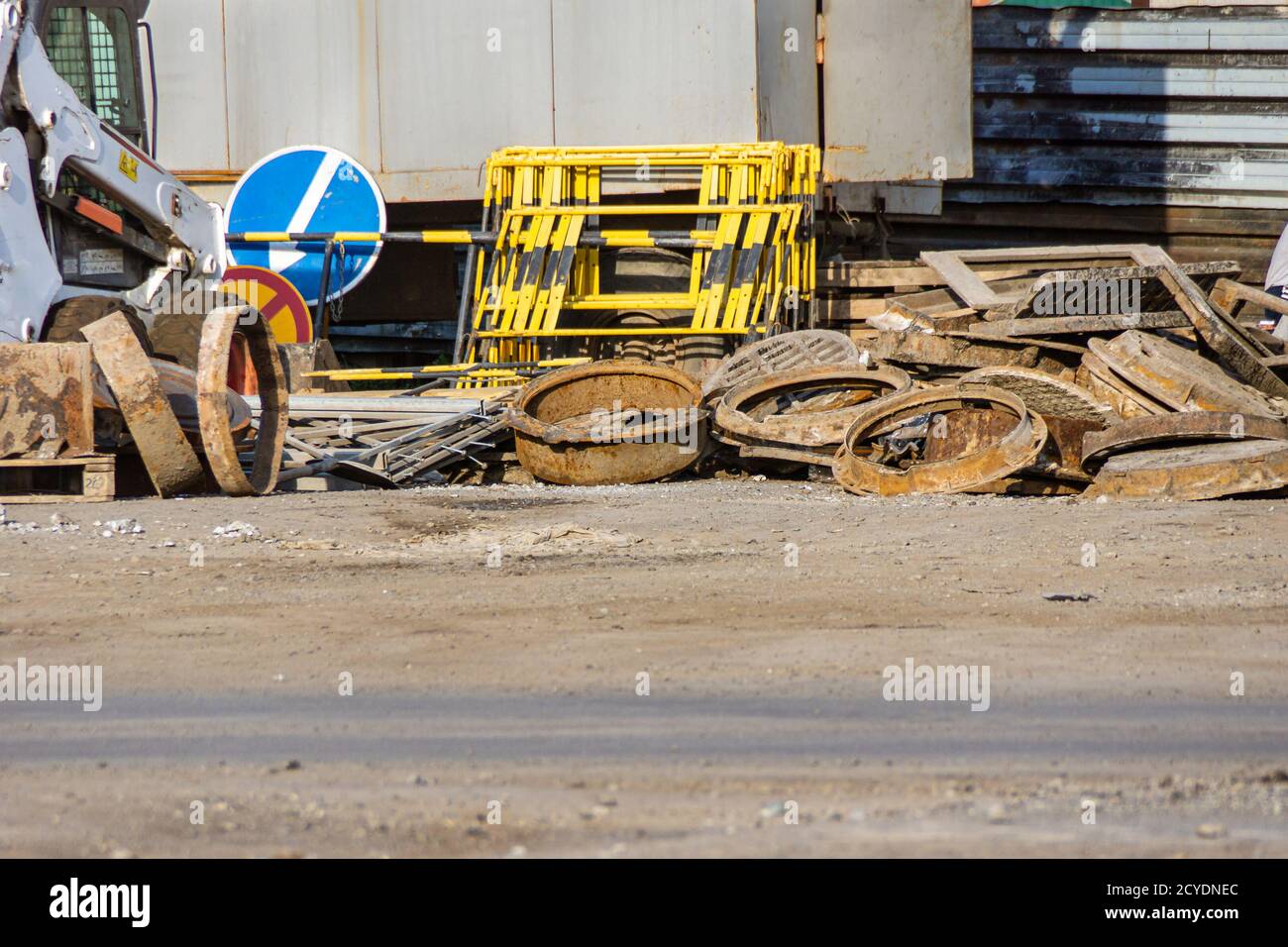 la maggior parte delle vecchie tombini di pozzo di pozzo ben venduti accatastati in un mucchio, vicino ai cartelli stradali temporanei e alle barriere di emergenza Foto Stock