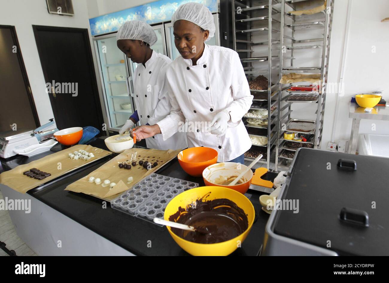 Operai artigiani preparano stampi di cioccolato all'interno della fabbrica di cioccolato assoluto nella capitale del Kenya Nairobi 20 marzo 2015. Il consumo di cioccolato nell'Africa subsahariana è in aumento. Secondo la società di ricerche di mercato Nielsen, le vendite in Sud Africa, il mercato più grande del continente, sono salite a 6.4 miliardi di rand (531 milioni di dollari) nel 2014 rispetto ai 5.8 miliardi di rand del 2013. In Kenya, Naheed Ahmed ha iniziato Absolute Chocolate a novembre dopo aver ottenuto il suo primo assaggio di cioccolato alla scuola culinaria in Sud Africa. Ora produce 100 chilogrammi al mese, vendendo i suoi tartufi infusi di peperoncino da sotto il vetro Foto Stock