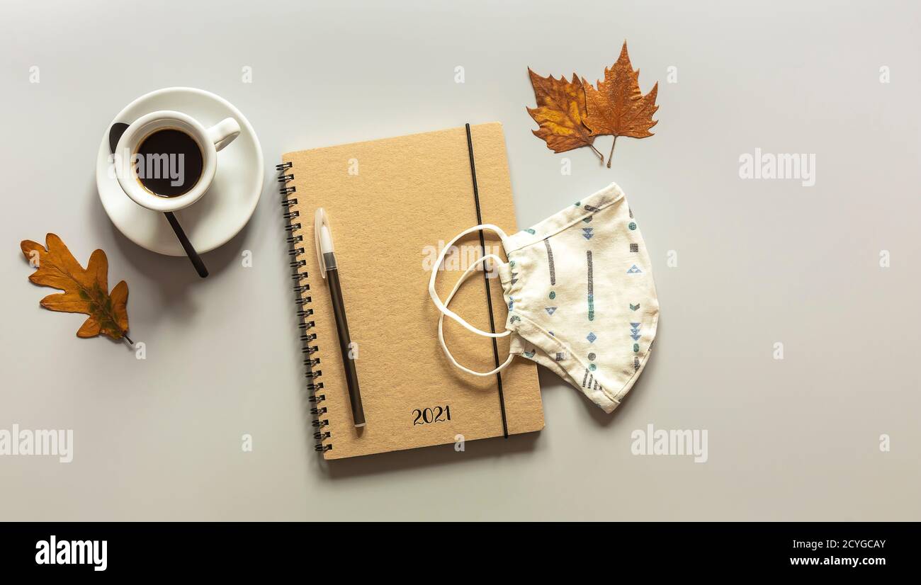 Spazio di lavoro con notebook, penna, foglie autunnali e tazza da caffè. Foto Stock