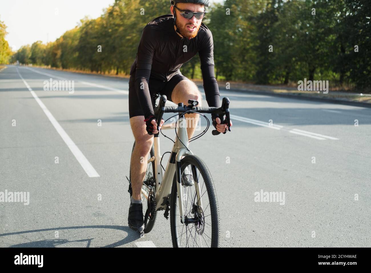 Immagine ravvicinata di un ciclista stradale su una ghiaia. Allenamento in bicicletta all'aperto, bicicletta e sportivo dall'aspetto moderno, stile di vita attivo Foto Stock