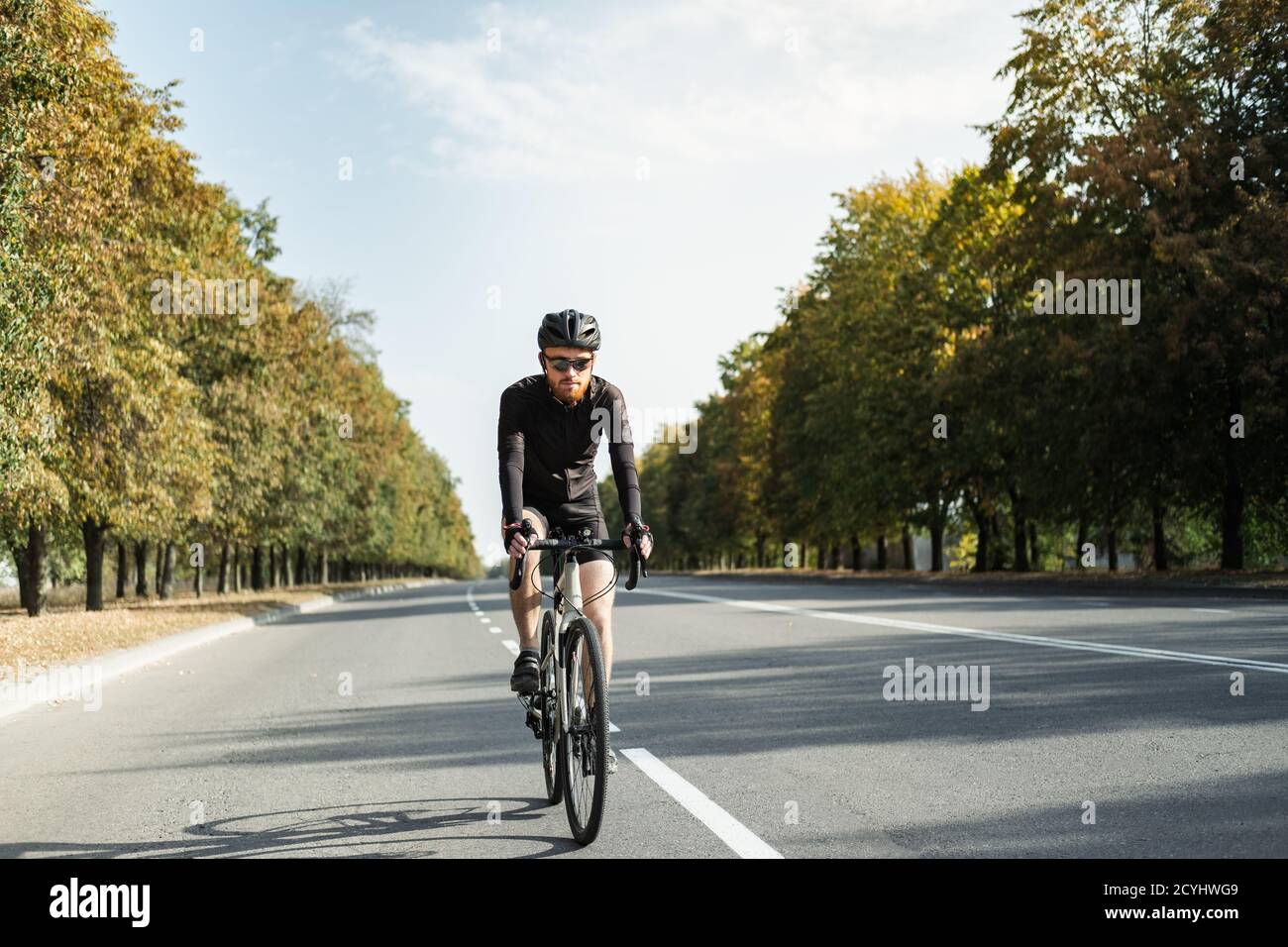 Uomo su una bici di ghiaia sulla strada. Ciclista ben attrezzata che guida una bicicletta moderna all'aperto Foto Stock