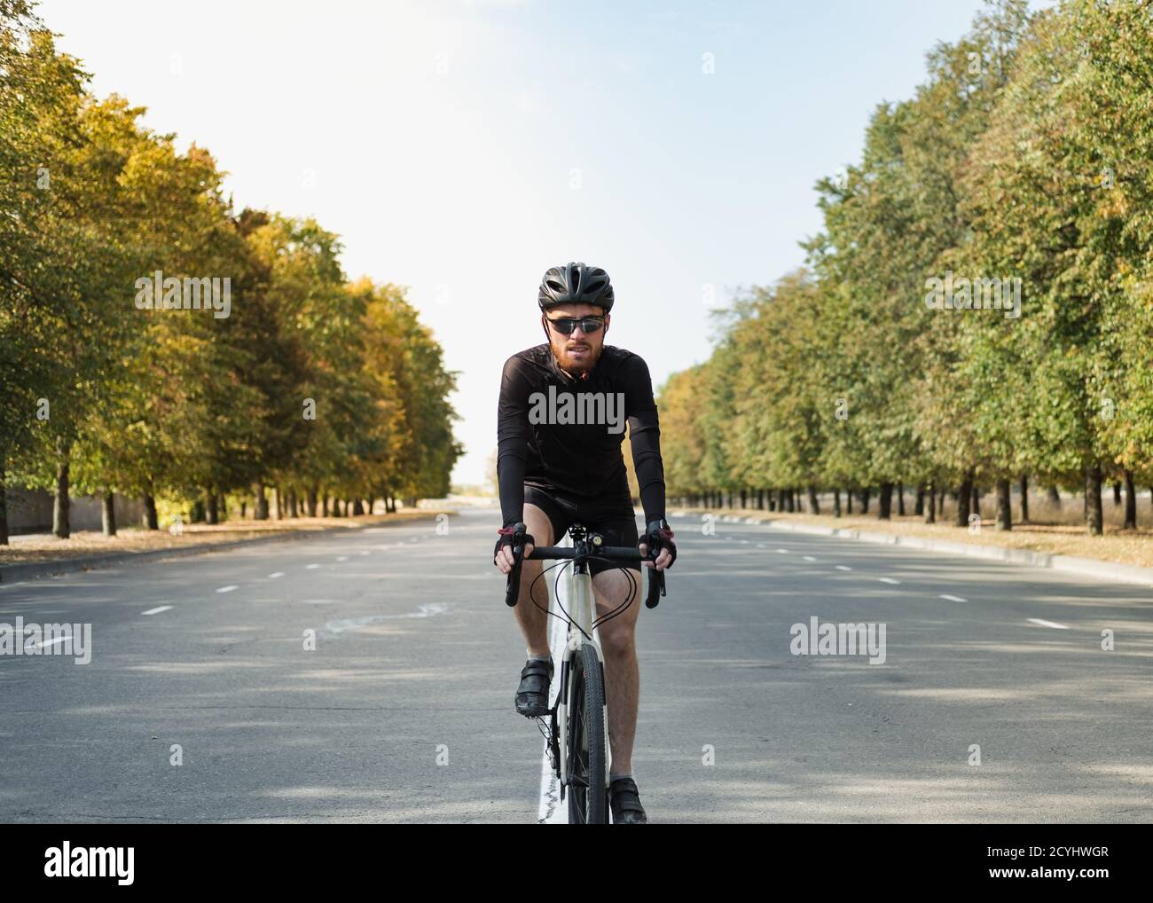 Ritratto di un uomo su una bici di ghiaia sulla strada. Ciclista ben attrezzata che guida una bicicletta moderna all'aperto Foto Stock