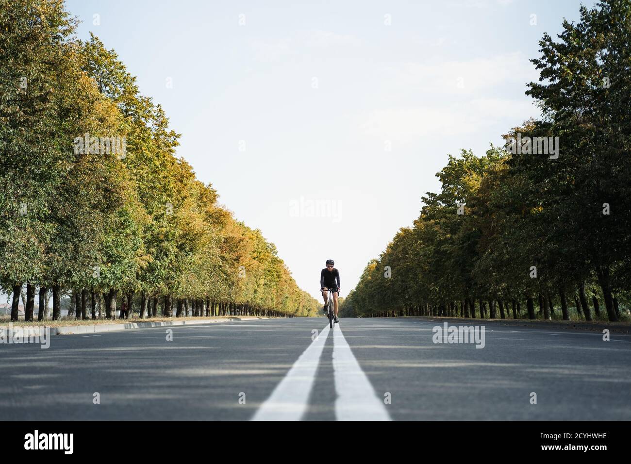 L'uomo guida una bici di ghiaia nella corsia centrale della strada. Ciclista ben attrezzata su una bicicletta moderna all'aperto, immagine simmetrica Foto Stock
