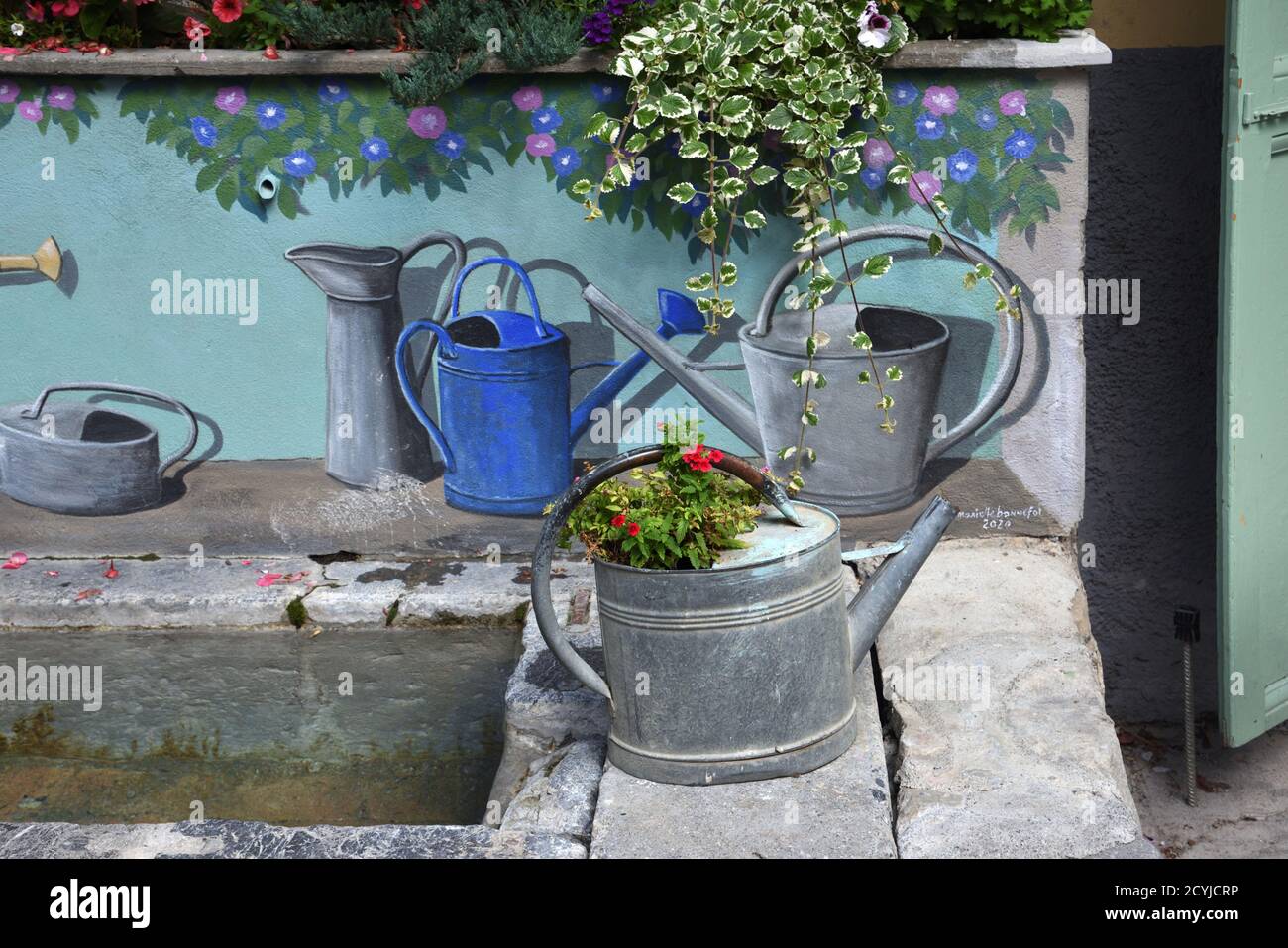Annaffiatoio vintage o Old Metal e lattine di annaffiatura dipinte Decorazione Fontana del villaggio o Fontana di strada Colmars-les-Alpes Provenza Francia Foto Stock