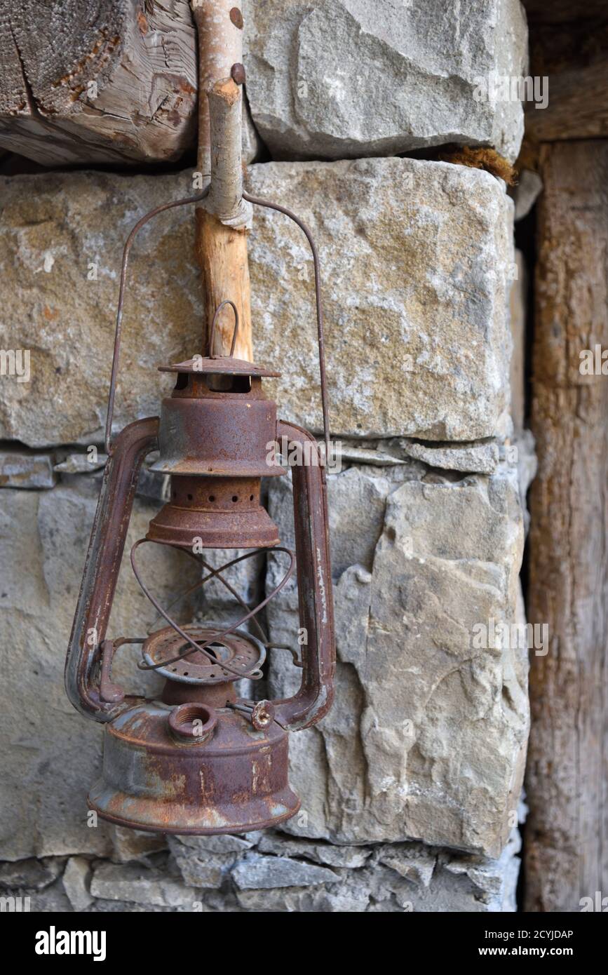 Old Rusty Oil lampada Hanging su rustico gancio di legno in Muro di pietra Foto Stock