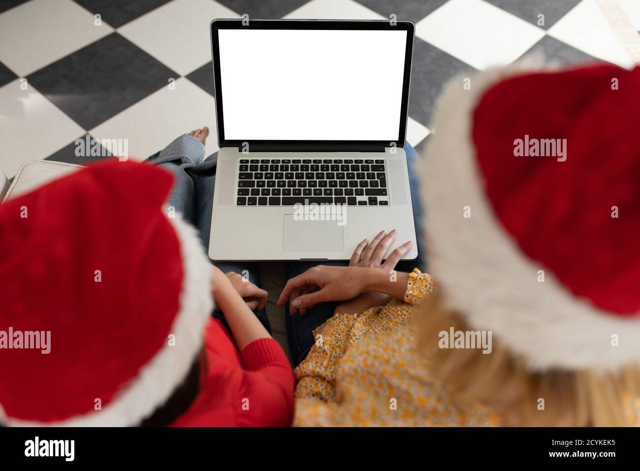 Madre e figlia in cappello di Santa usando il laptop a casa Foto Stock