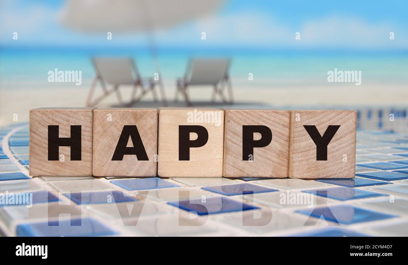 Happy parola cubetti di legno su sfondo oceano. Concetto di stile di vita Foto Stock