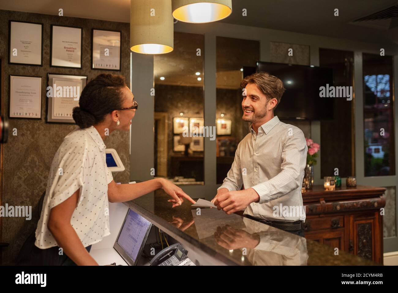 Un addetto alla reception dell'hotel che parla con un cliente che effettua il check-in in hotel. Foto Stock