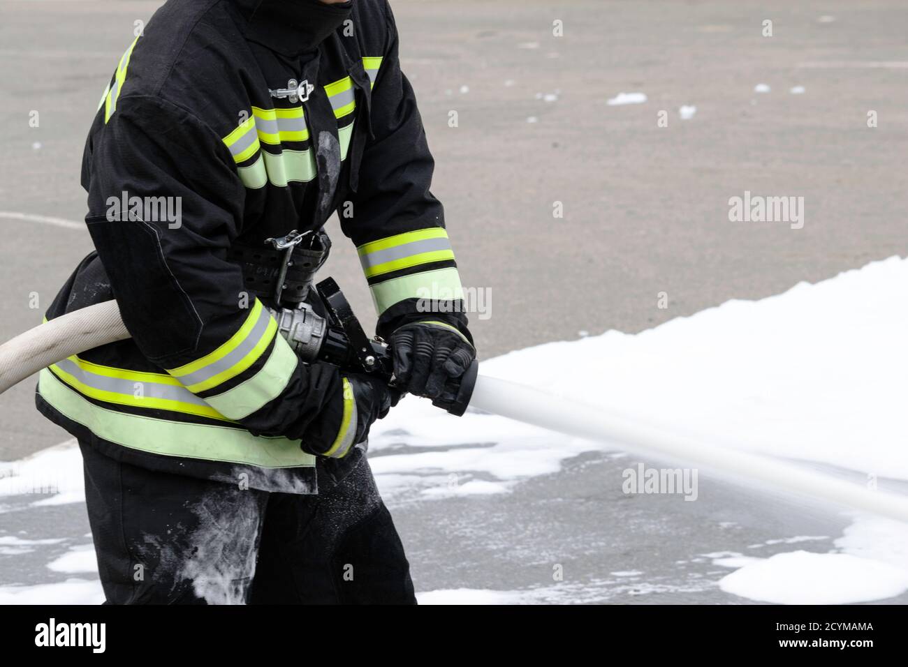Nutrendo schiuma dal combattente antincendio portatile, la schiuma antincendio fuoriesce dal tronco, che mantiene il vigile del fuoco in abiti da combattimento Foto Stock