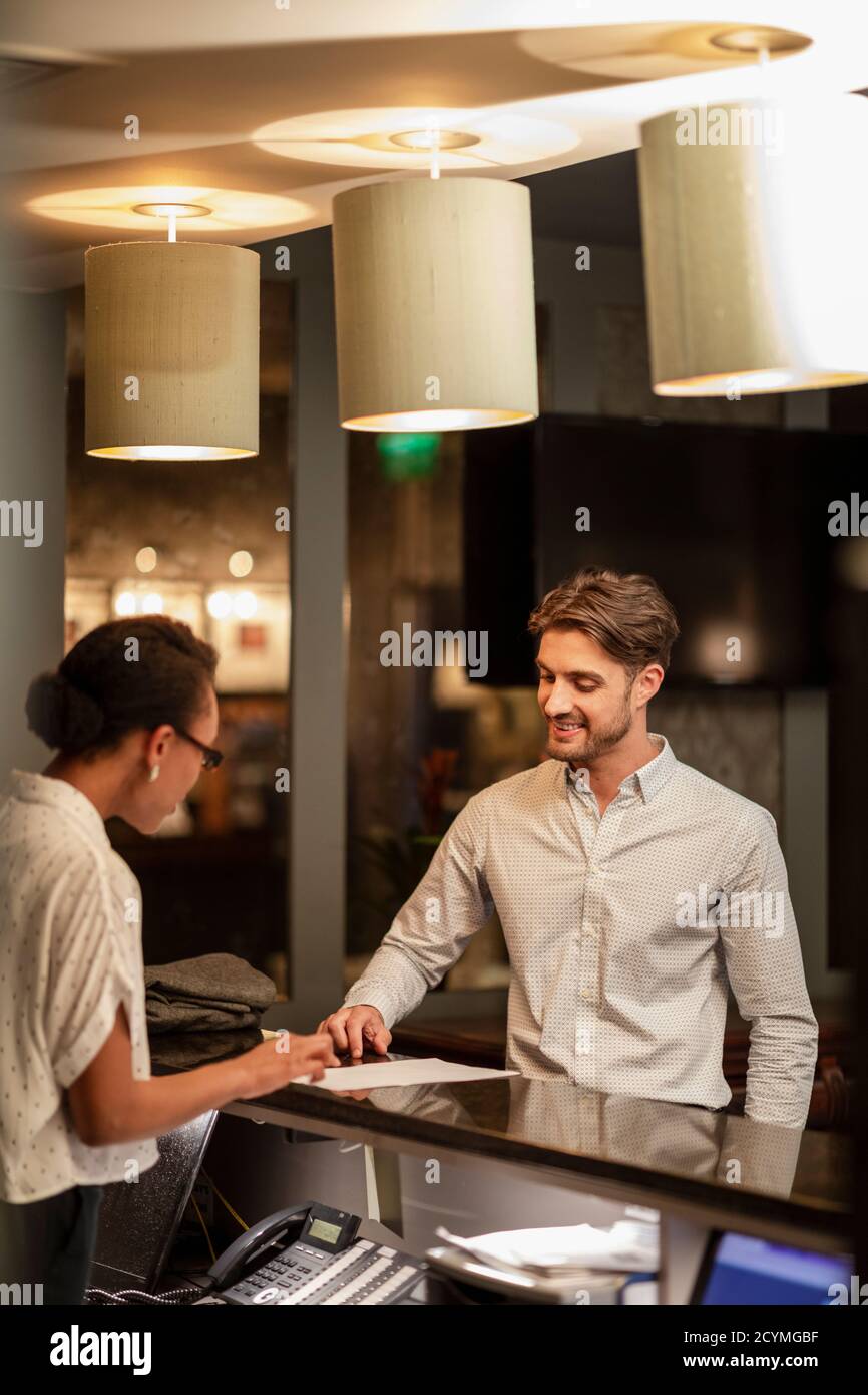 Un addetto alla reception dell'hotel che parla con un cliente che effettua il check-in in hotel. Foto Stock