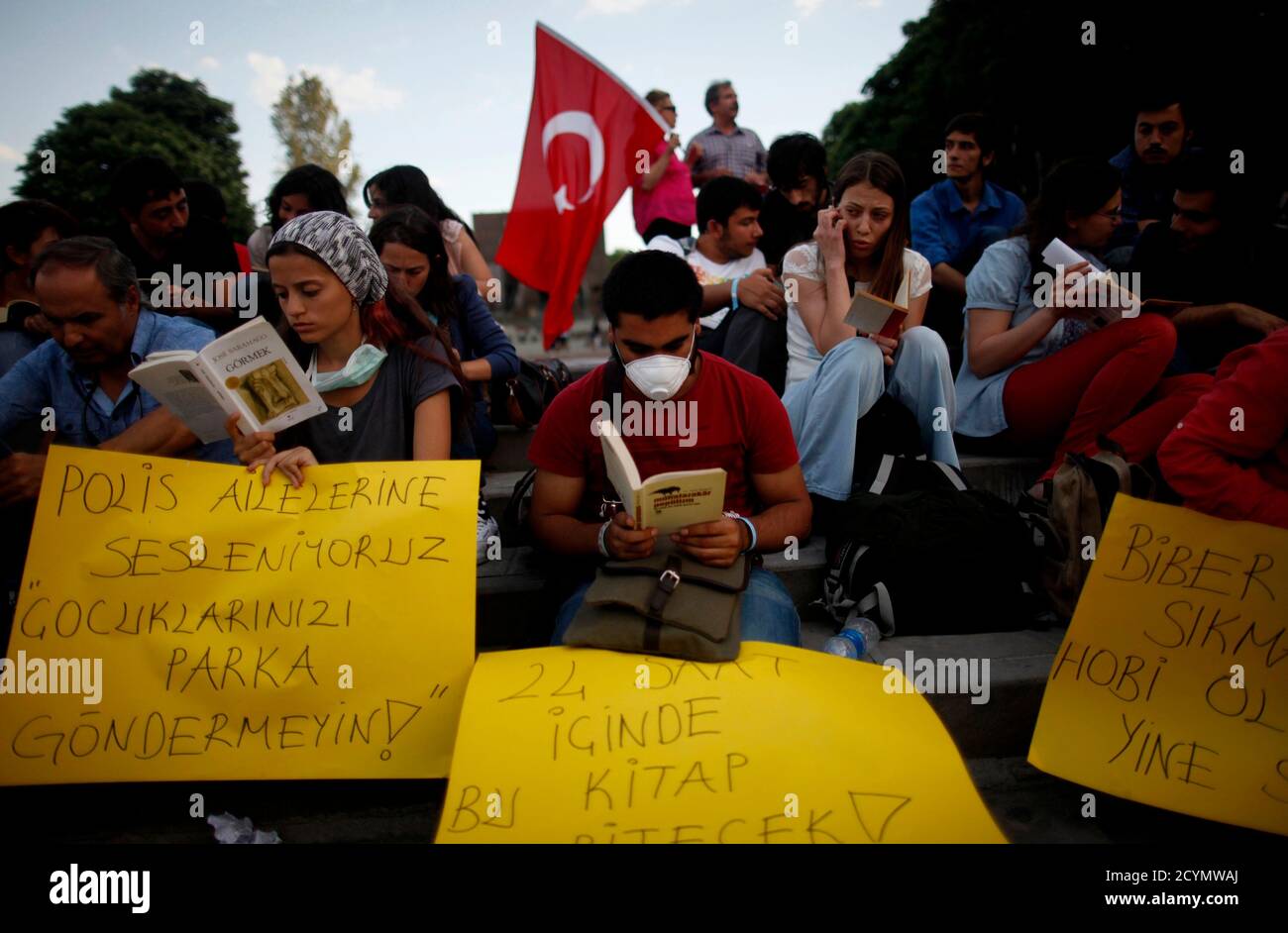 I manifestanti anti anti anti-governativi hanno letto i libri in piazza Kizilay, nel centro di Ankara, il 12 giugno 2013. Circa 50 manifestanti si sono riuniti in piazza per leggere libri nel tentativo di aggirare i divieti della polizia contro le riunioni di massa e le proteste nella capitale. Mercoledì il presidente della Turchia ha chiesto un dialogo con i manifestanti legittimi dopo che la polizia in rivolta ha autorizzato la piazza di Istanbul, al centro di quasi due settimane di protesta contro il primo ministro Tayyip Erdogan. Sul cartello a sinistra si legge: 'Stiamo parlando ai genitori della polizia antisommossa: Non mandare i vostri bambini al parco'. REUTERS/Dado Ruvic (TUR Foto Stock