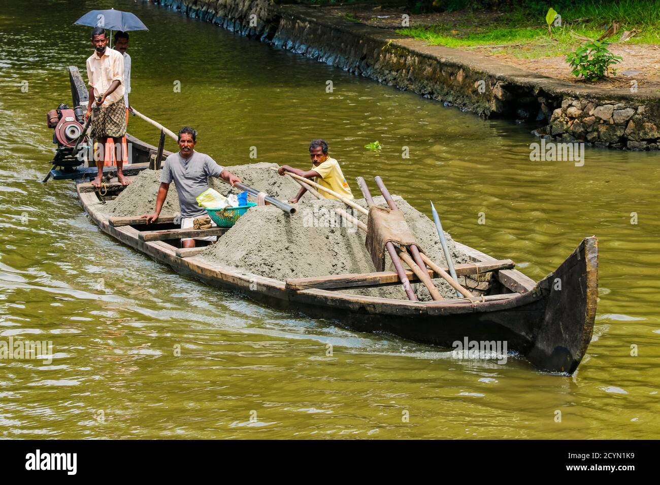 Operai su piccola chiatta carico di cemento per la costruzione in un distretto locale di backwaters di questa regione di crociera; Alappuzha (Alleppey), Kerala, India Foto Stock