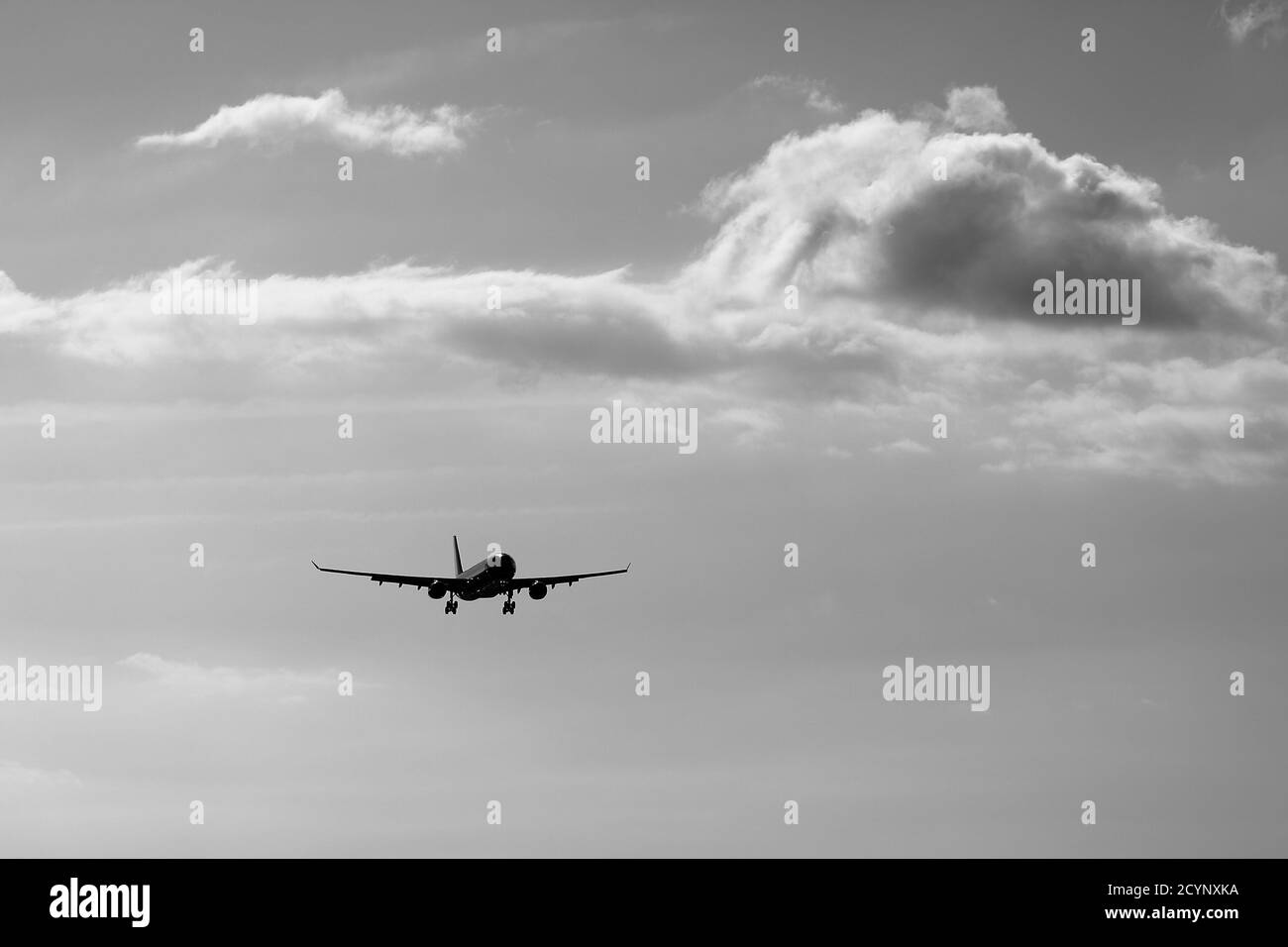 un aereo che vola nel cielo con nuvola in monocromia Foto Stock