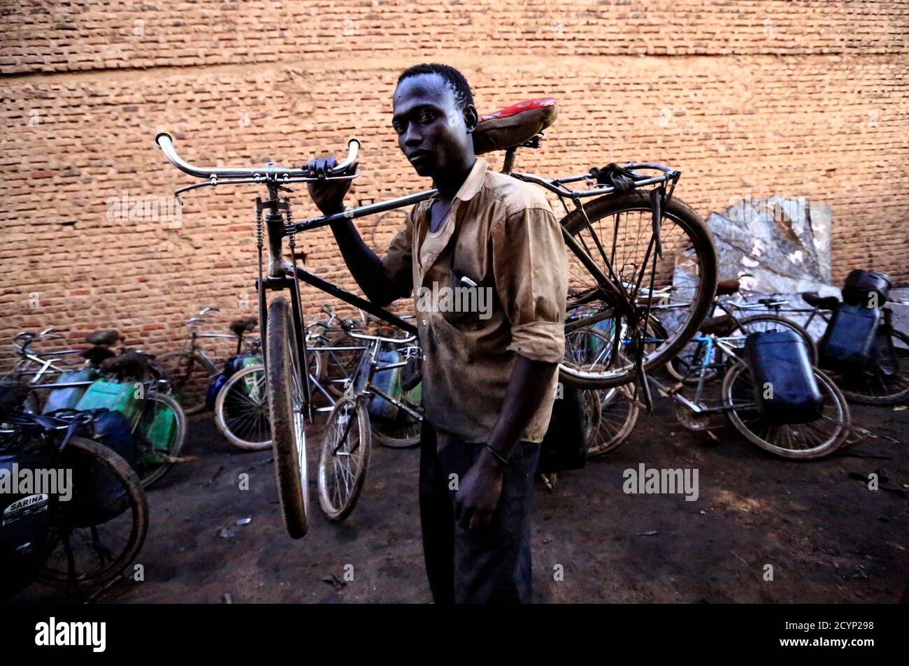 Un uomo porta la sua bicicletta sopra le spalle dopo aver fatto la sua  consegna di olio usato nella capitale Khartoum, 29 ottobre 2014. Lo stato  povero dell'economia sudanese ha costretto molte