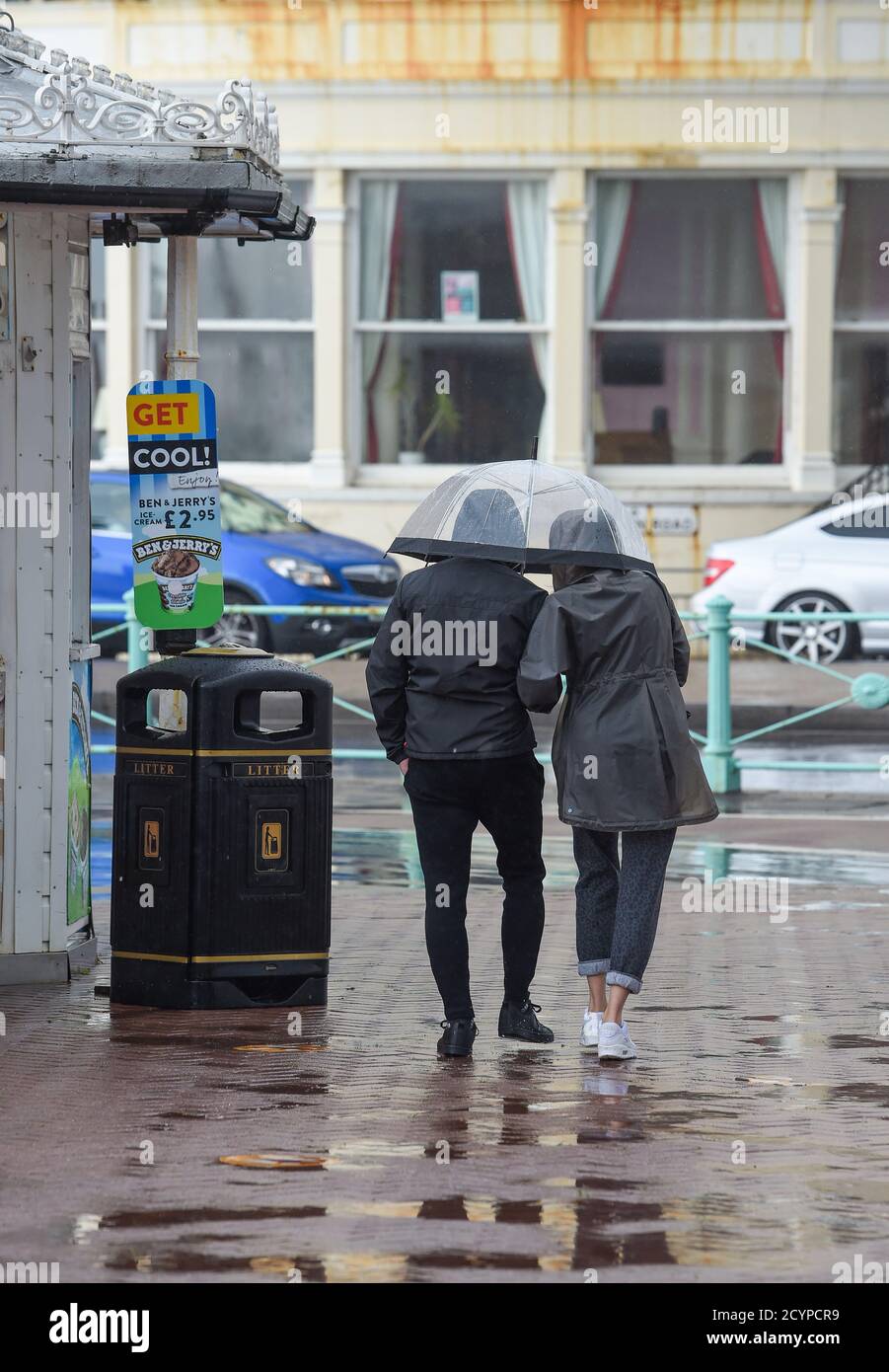 Brighton UK 2 ottobre 2020 - UNA coppia cerca di rimanere asciutto sotto un ombrello nel vento guida e pioggia sul lungomare di Brighton come Storm Alex spazzare attraverso la Gran Bretagna portando forti venti e pioggia soprattutto nelle zone meridionali: Credit Simon Dack / Alamy Live News Foto Stock