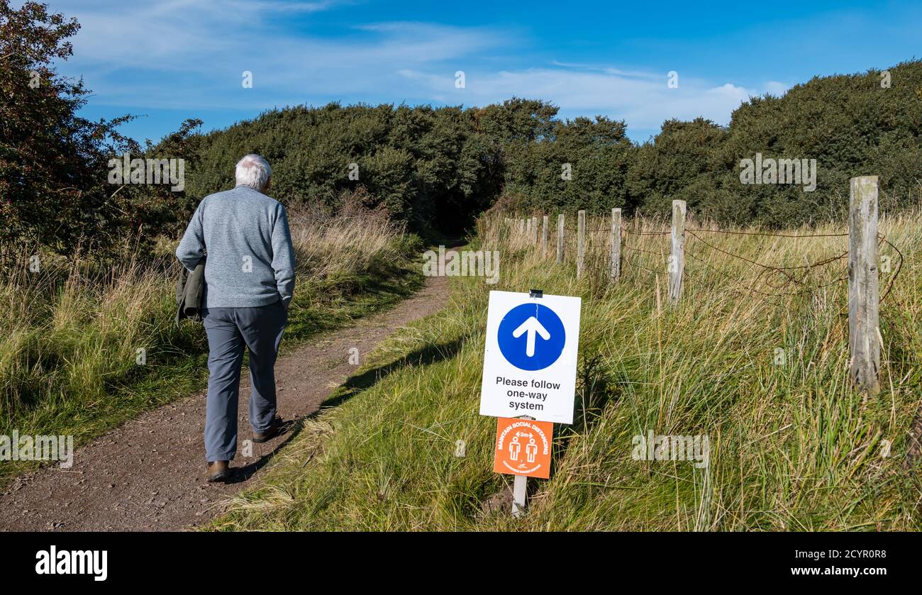 Aberlady Nature Reserve, East Lothian, Scozia, Regno Unito, 2 ottobre 2020. Regno Unito Meteo: Una bella giornata di sole sulla costa del Firth of Forth. Un uomo anziano abita dal sistema di distanziamento sociale unidirezionale Foto Stock