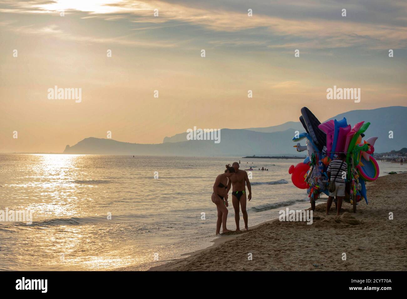 vista panoramica di una spiaggia con un paio di turisti Relax sulla riva del Mar Tirreno e un fornitore con il suo carrello caricato con giocattoli Foto Stock