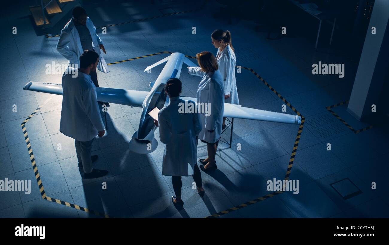 Riunione degli ingegneri aerospaziali lavorare sul prototipo di drone di un veicolo aereo senza equipaggio. Scienziati dell'aviazione in White Coats parlando. Laboratorio industriale con Foto Stock