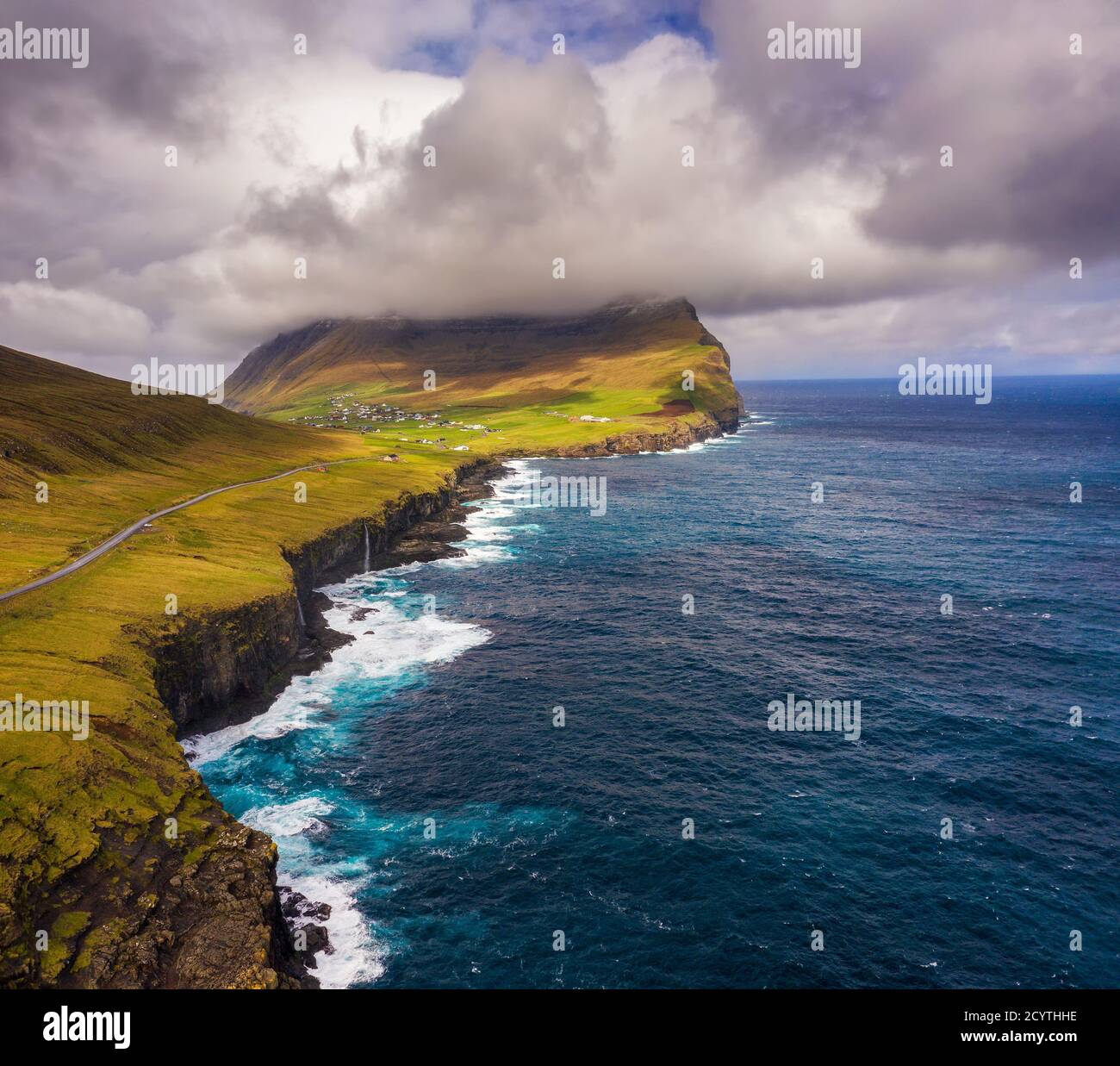 Veduta aerea di una strada che va lungo la costa ad un villaggio sulle Isole Faroe Foto Stock