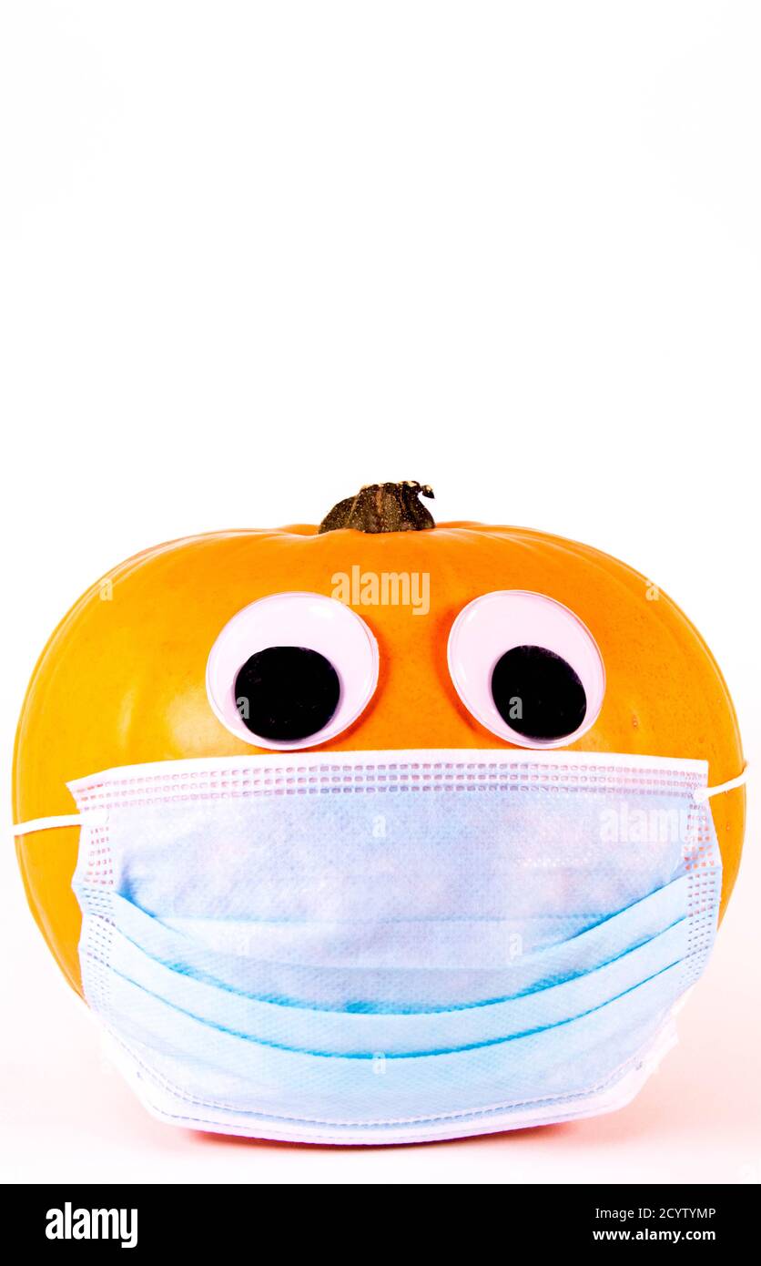 Una zucca di Halloween, con gli occhi, indossando una maschera chirurgica durante la pandemia del virus. Foto Stock