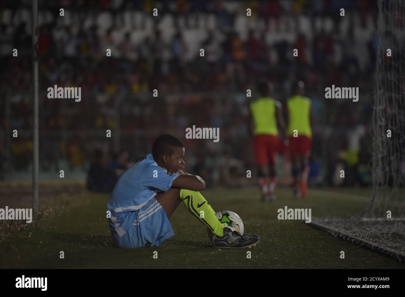 Un ragazzo di palla si siede dietro la rete di obiettivo nelle finali del torneo di calcio del Distretto di Mogadiscio tra i distretti di Waaberi e Shibis la sera del 24 settembre 2018. La partita di calcio è stata la seconda nella storia recente ad essere disputata di notte a Mogadiscio, segnalando un ritorno alla normalità per un paese che esce da più di due decenni di guerra civile. Foto Stock