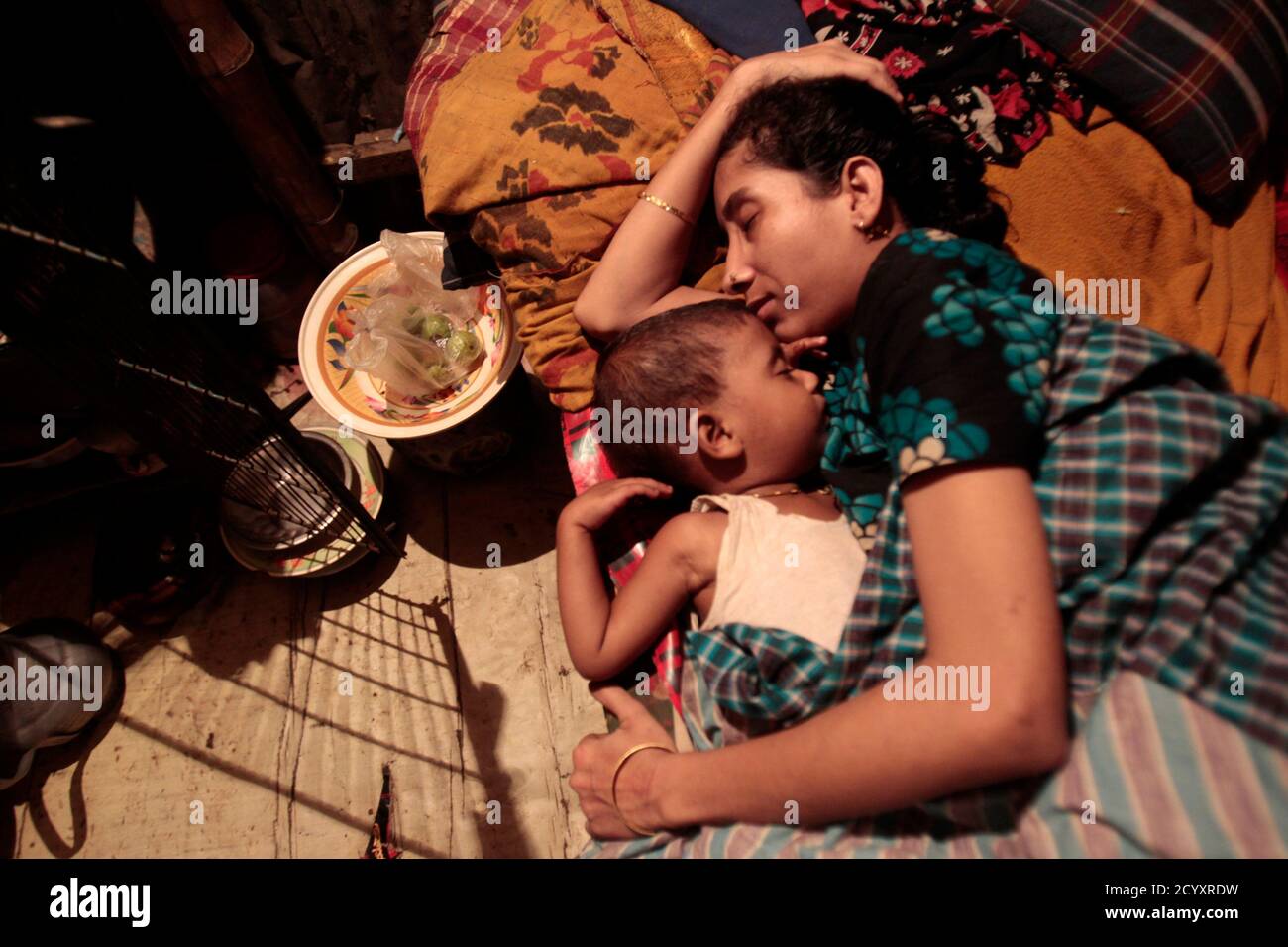 Hosna Ara dorme con suo figlio all'interno della sua casa di baraccopoli a  Hatirjheel a Dhaka 28 luglio 2012. Hosna Ara lavora in una fabbrica di  abbigliamento come assistente. Guadagna 3,000 TK (
