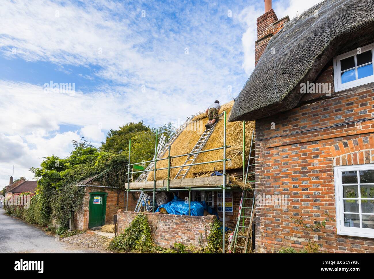 Un thatcher esperto al lavoro che sostituisce il tetto tradizionale di paglia di un vecchio cottage in Great Bedwyn, un villaggio nel Wiltshire orientale, Inghilterra meridionale Foto Stock