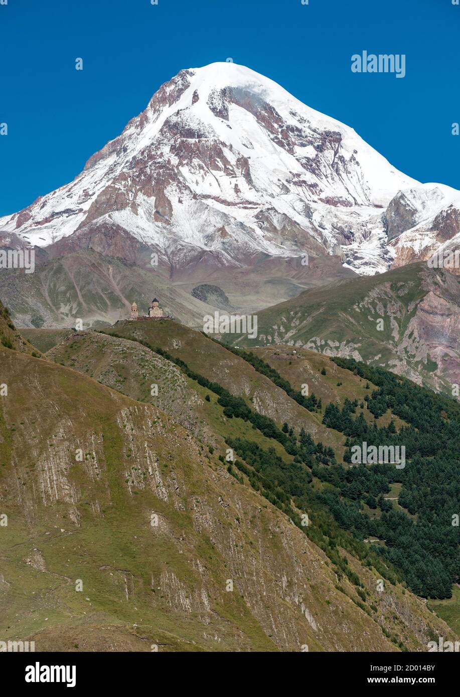 Mount Kazbek (5047m) e Gergeti Trinity Church nelle montagne del Caucaso del nord della Georgia. Foto Stock