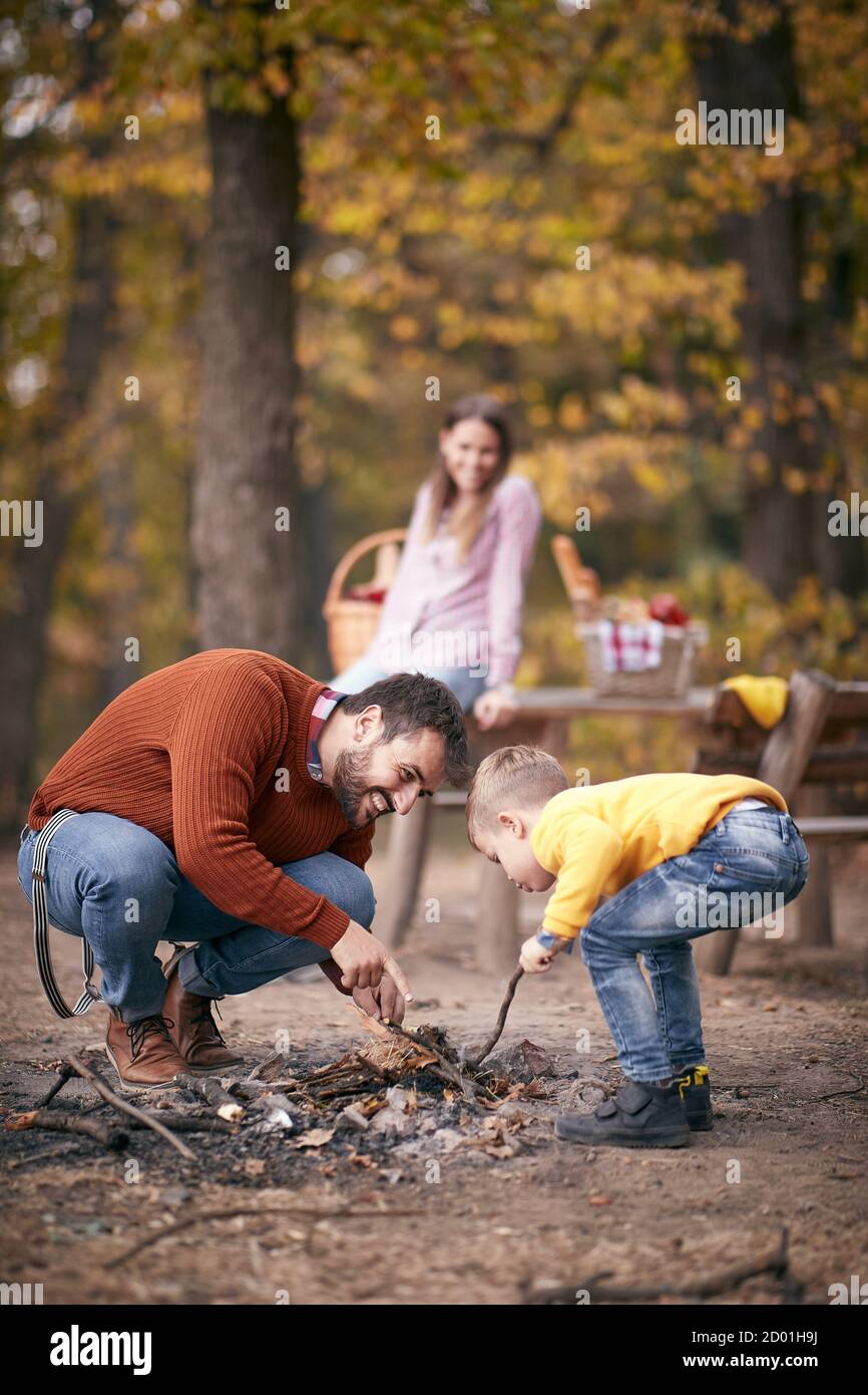Padre e figlio avviano un fuoco insieme su un campeggio; concetto di tempo familiare di qualità Foto Stock