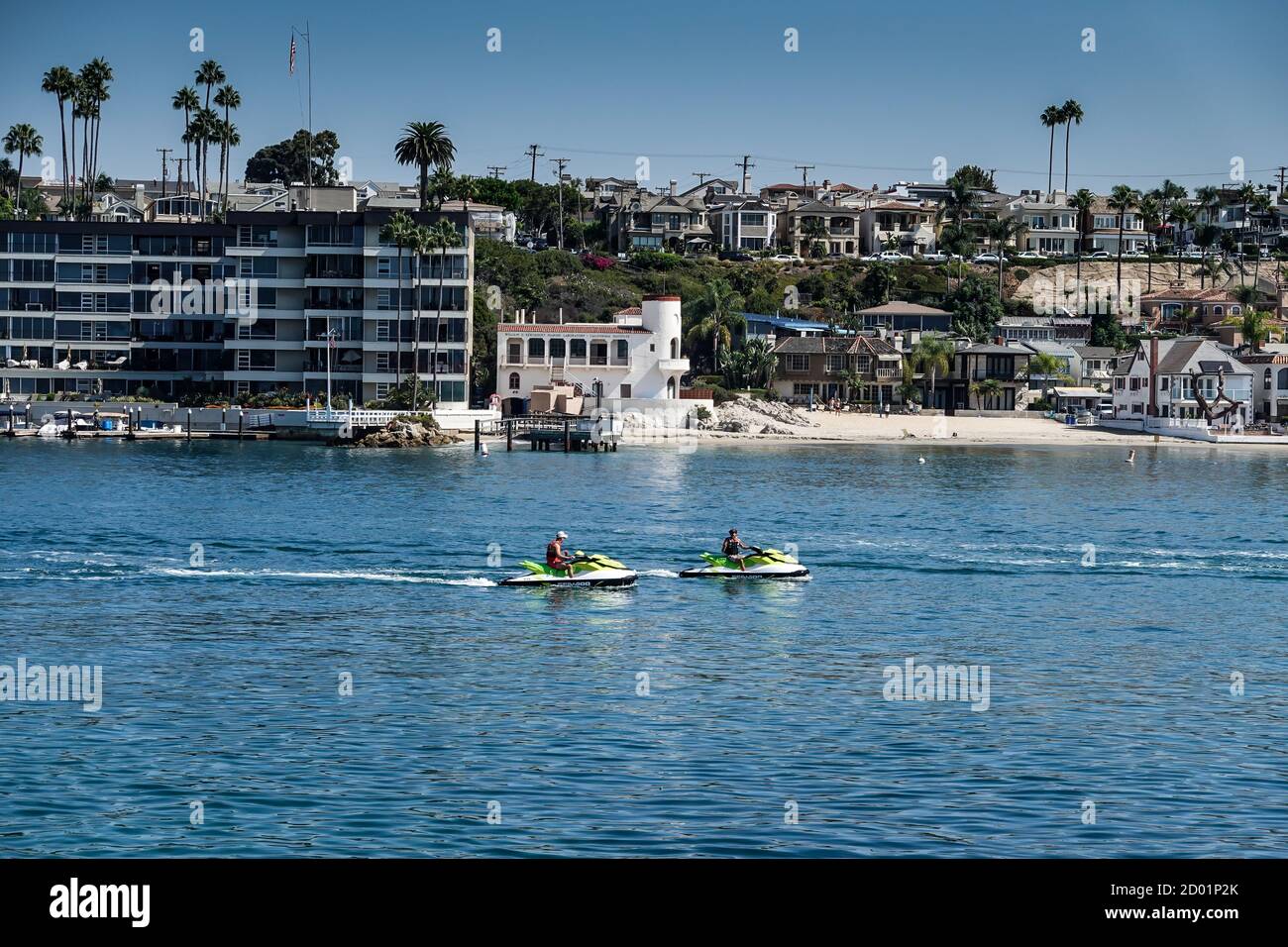 Moto d'acqua nel canale d'ingresso del porto di Newport Beach con lussuose case e proprietà fronte oceano a Corona del Mar sullo sfondo. California Foto Stock